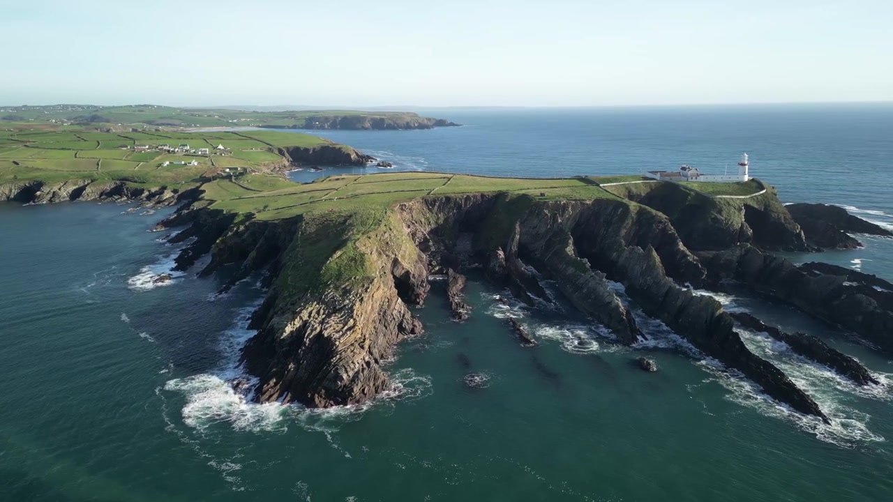 Drone flyver baglæns over kystnære West Cork, afslører langsomt et bredt panorama med klipper og fyrtårn ved Galley Head, Irland