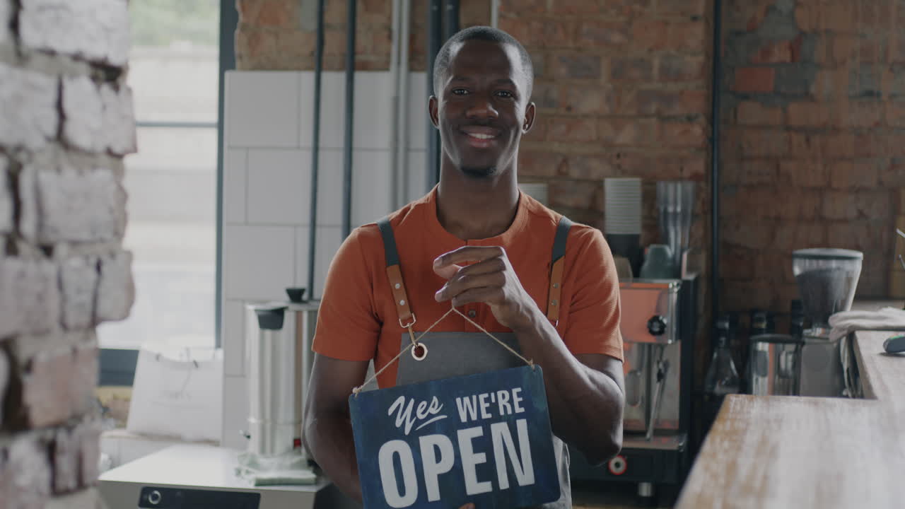 Smilende barista holder åbent-skilt