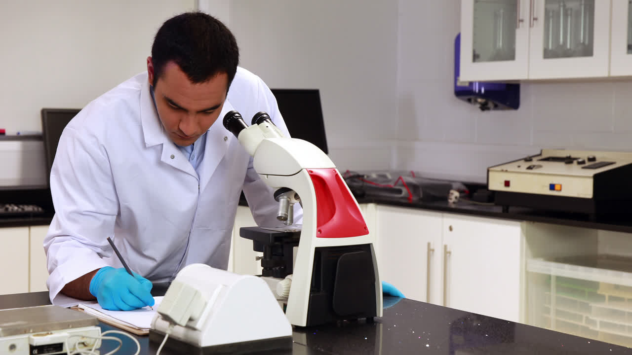 Young scientist looking through microscope in the lab