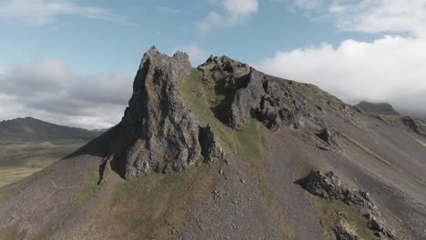 dolly back view, icelandic mountain towering in distance, sunny day