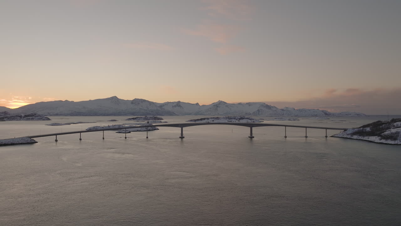 석양에 눈 덮인 산에서 물 위에 다리의 아름다운 공중 샷