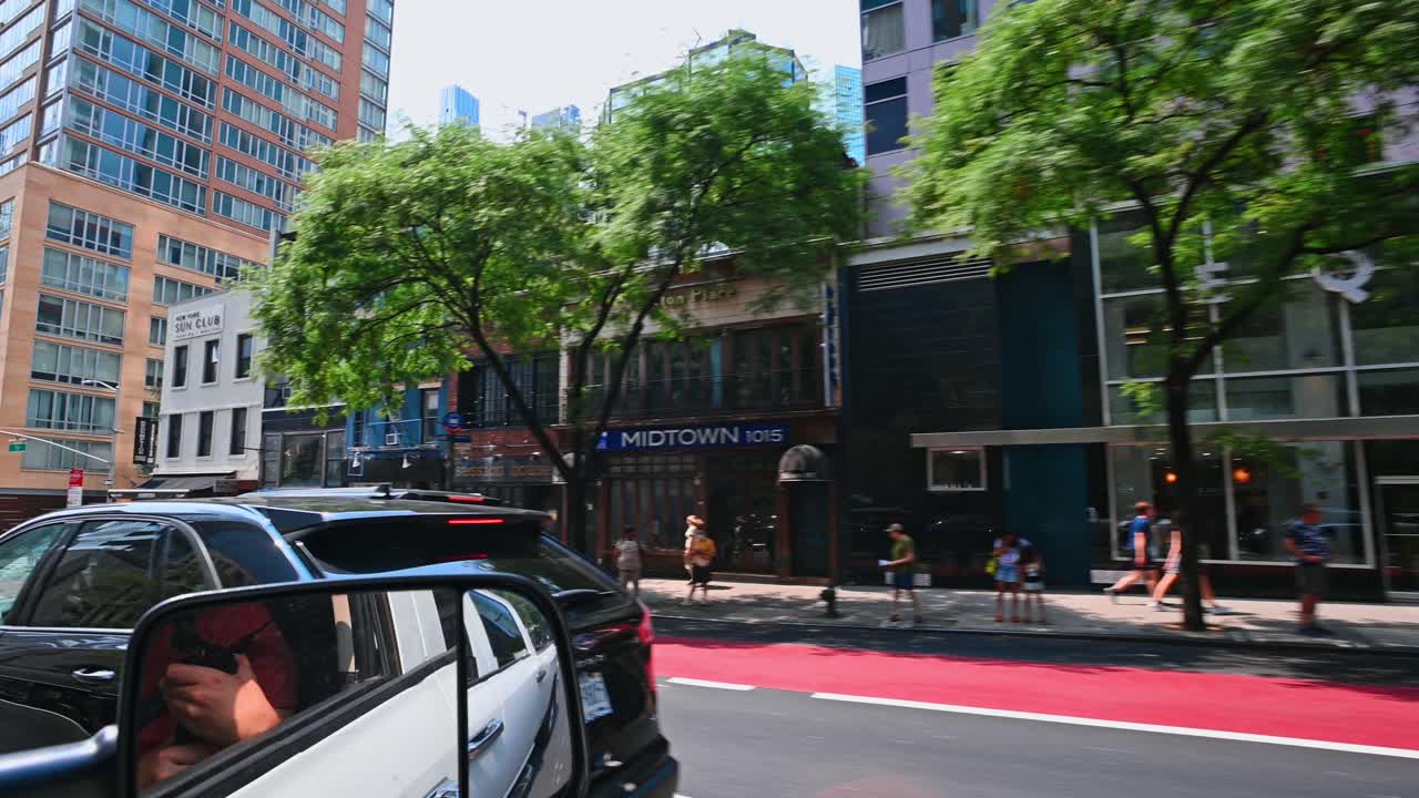 New York, USA, 5 August 2025: Modern glass skyscrapers and street trees in Midtown Manhattan. Corner view of a contemporary glass office building with green trees and city traffic at an intersection
