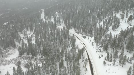 Toma-De-Inclinación-Aérea-Que-Revela-Una-Peligrosa-Carretera-De-Montaña-Cubierta-De-Nieve-En-Un-Día-Nublado