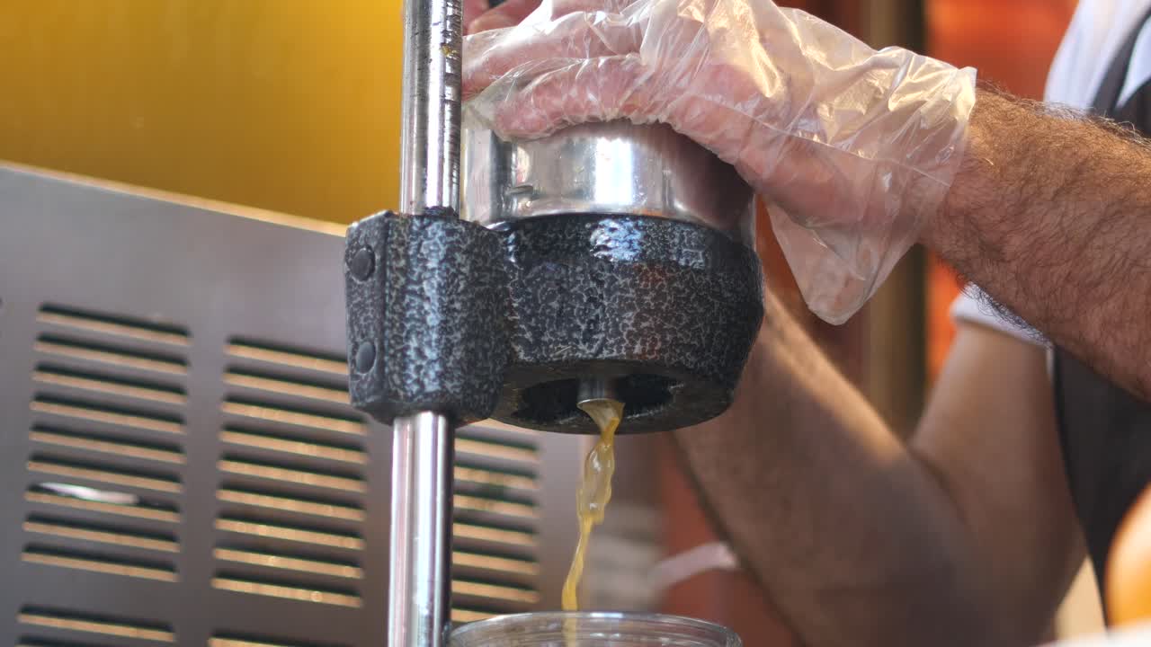 한 사람이 오렌지를 러서 신선한 주스를 만들고 있습니다.