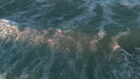 Olas-Rompiendo-Y-Haciendo-Espuma-En-El-Agua-Azul-Verdosa-Del-Océano-Desde-Una-Vista-Aérea