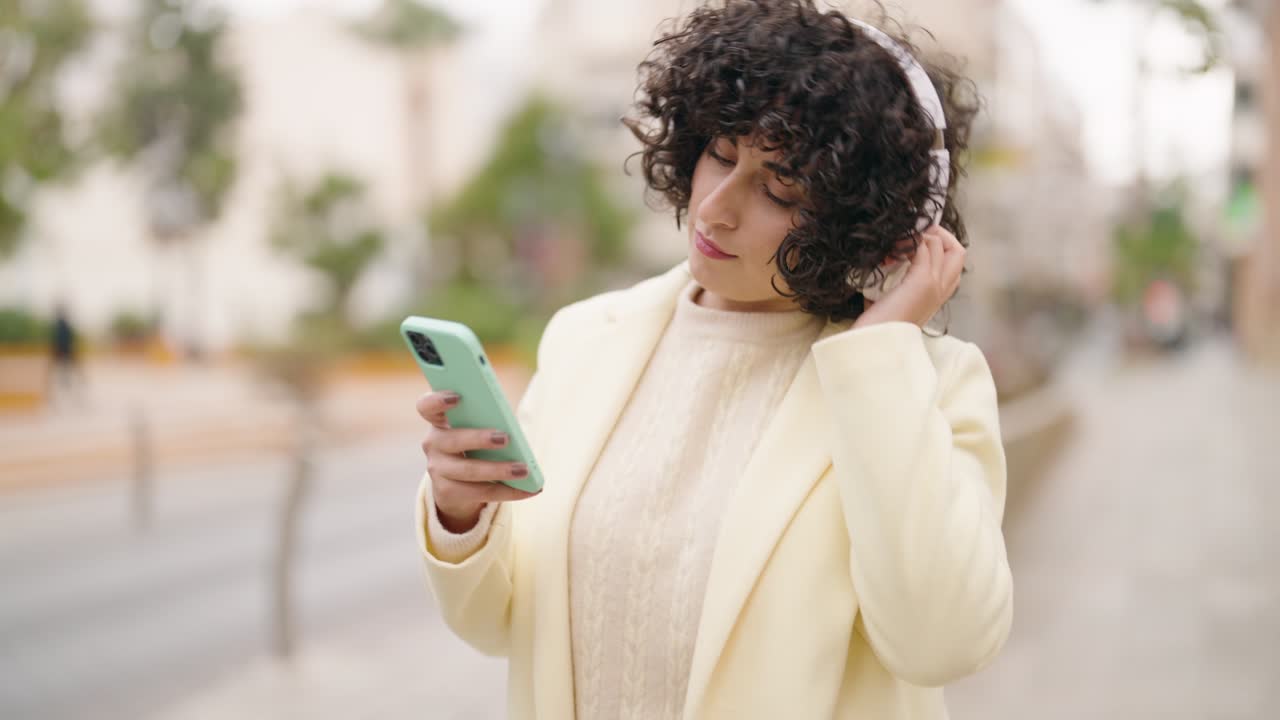mujer joven sonriendo confiada escuchando música en la calle