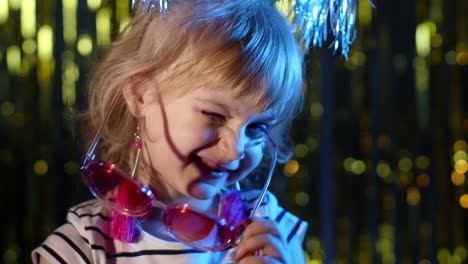 Stylish-trendy-child-kid-in-sunglasses-at-disco-party-cyberpunk-club-looking-at-camera-and-smiling