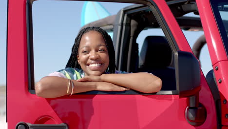 Una-Joven-Afroamericana-Se-Apoya-En-La-Puerta-De-Un-Auto-Rojo-En-Un-Viaje-Por-Carretera