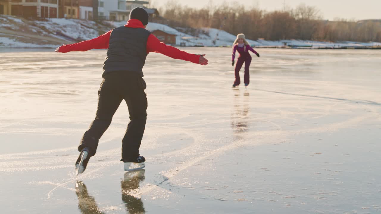 Father and daughter ice skating on a frozen lake