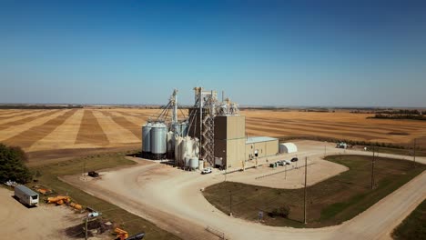 slow cinematic rising aerial drone shot of a grain elevator with farmland crops landscape