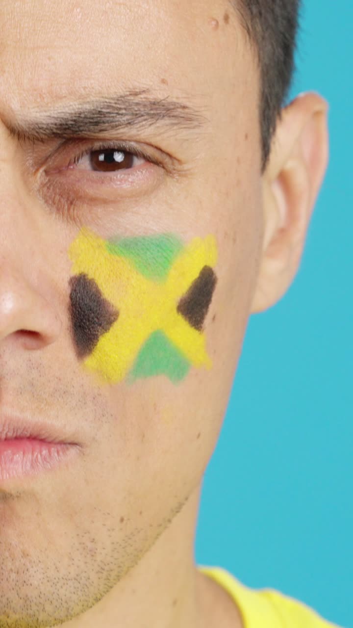 Serious man with a jamaican flag painted on the face