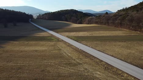 Weite-Landschaft-Mit-Einem-Vorbeifahrenden-Auto-Bei-Sonnenuntergang