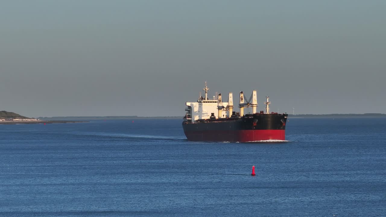 토미니 유니티 화물선은 해가 지는 동안 네덜란드의 강 물류로 이동하고 있습니다.