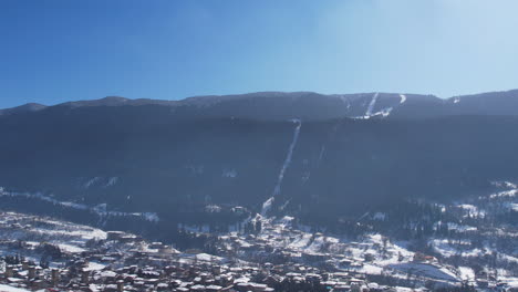 winter in the caucasus mountains: snow covered village and ski slope