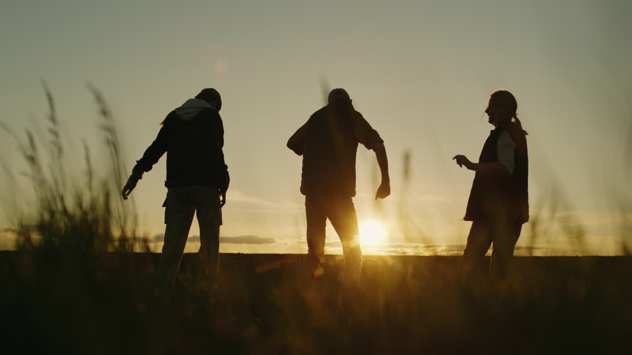 에서 해가 지는 동안 춤을 추는 친구들의 실루