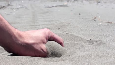 Eine-Hand,-Die-Den-Sand-Am-Strand-Berührt