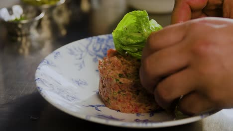 plato con tartar se sirve con una hoja en él