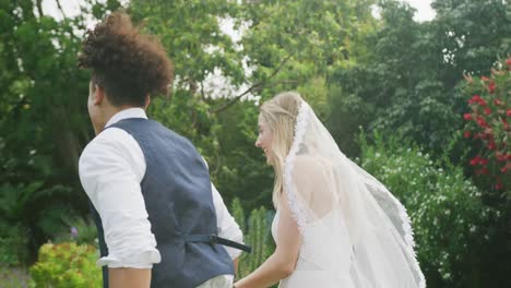 Glückliches,-Vielfältiges-Paar,-Das-An-Einem-Sonnigen-Tag-Bei-Der-Hochzeit-Im-Garten-Spaziert