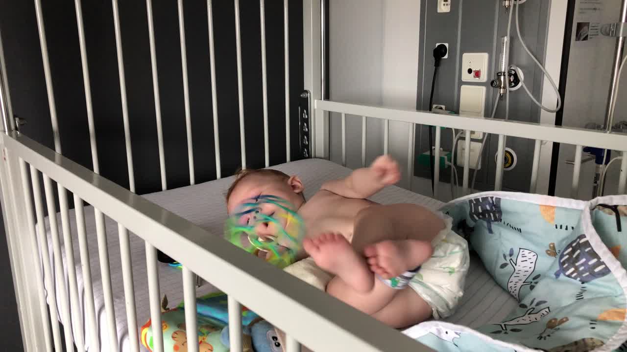 Bambina che cerca di rotolare e gioca con la sua palla colorata in ospedale