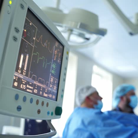 medical equipment in the operating room. screen showing waves of patient's heartbeat during surgical procedure. monitors on blur background of doctors