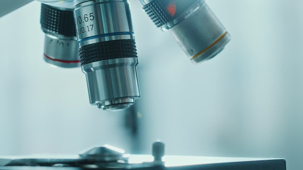 Three Objective Lenses Being Turned above Microscope Stage