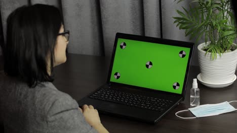 Woman-have-video-call-conference-on-laptop-with-green-screen.-Distance-work