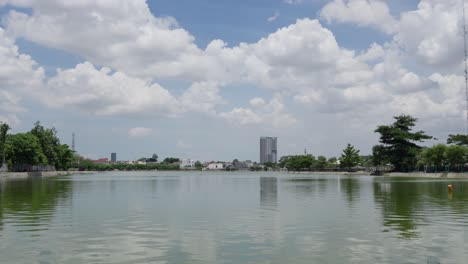 lake with city buildings and clouds in the sky in the background