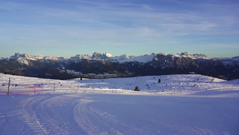 panning view of an empty ski piste in the alps with the epic snow capped mountains of the dolomites in the background