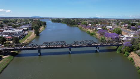 coches conduciendo en el puente kempsey sobre el río macleay con árboles de jacaranda en la orilla del río en nueva gales del sur, australia