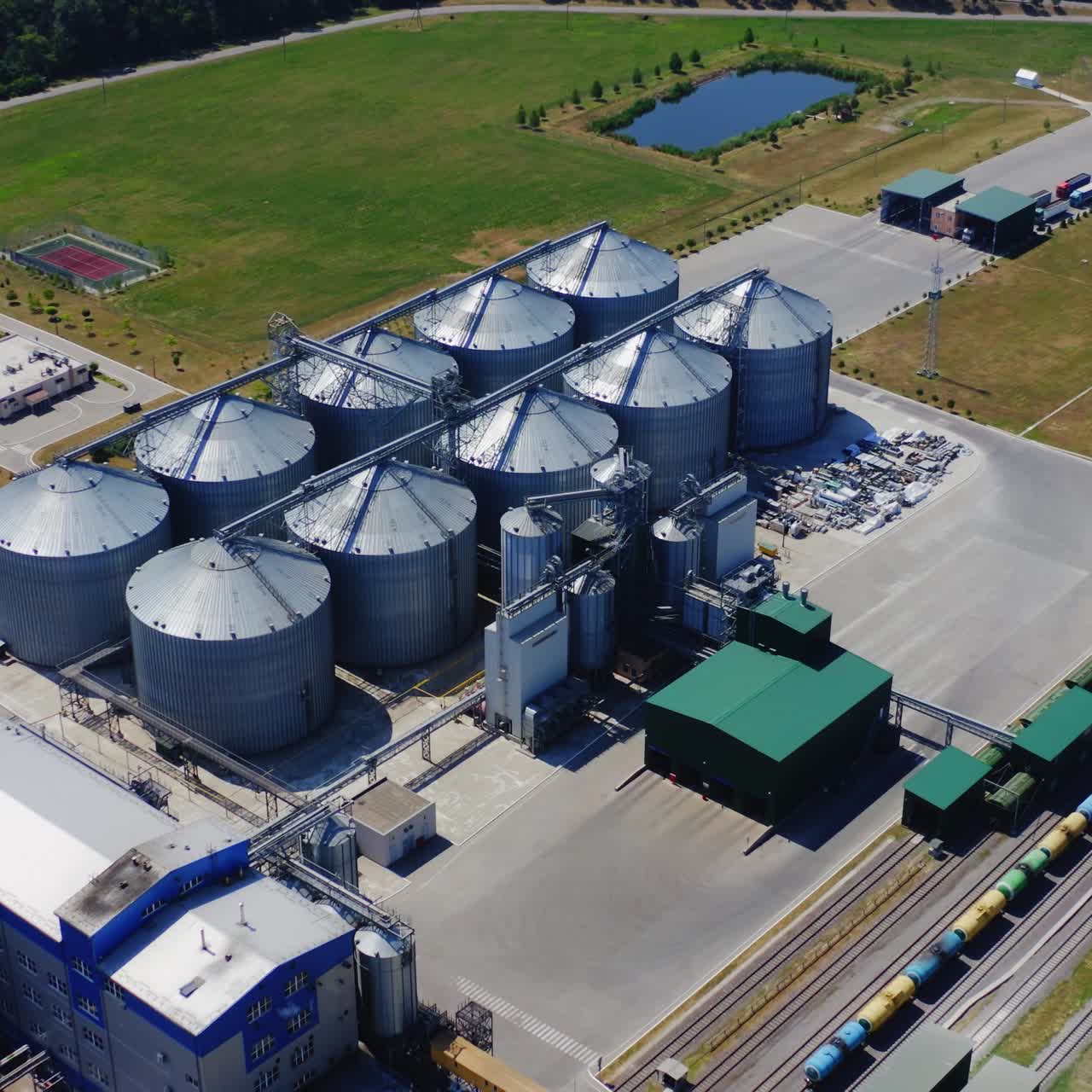Industrial grain storage. Modern plant for agribusiness on field. Silver silos for processing agricultural products. Aerial view.