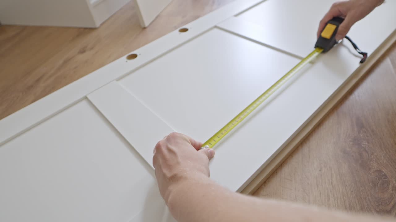Male hands use measuring tape to assemble closet door, moving task