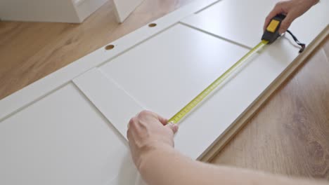manos masculinas usan cinta métrica para montar la puerta del armario, tarea de movimiento