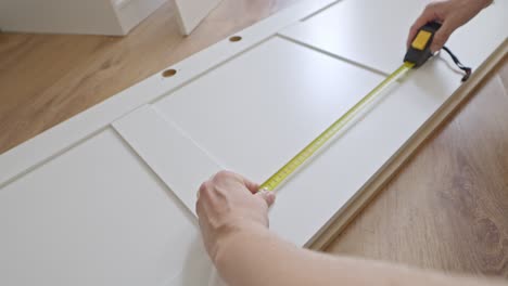 male hands use measuring tape to assemble closet door, moving task