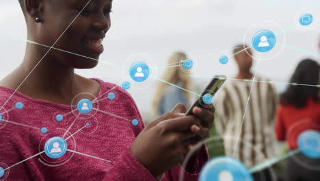 Animation-of-network-of-connections-with-icons-over-african-american-woman-using-smartphone