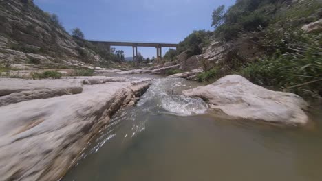 Niedriger,-Schneller-FPV-Drohnenflug-Durch-Die-Schmale-Felsenflussschlucht-Zur-Brücke