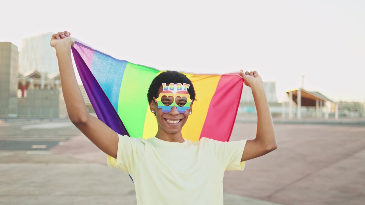 Happy Young Person Holding Rainbow Flag and Wearing LGBT Glasses