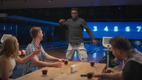 a happy black african-american man in a bowling club happily runs to his friends to celebrate the knocked out air. share the victory with friends. multi-ethnic group of friends