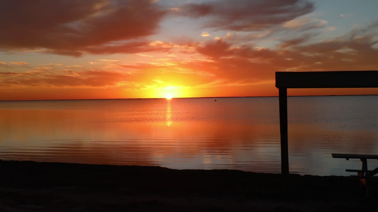 Matahari terbenam yang megah di atas muara Laguna Madres yang tenang di North Padre Island National Seashore di sepanjang Pesisir Teluk Texas