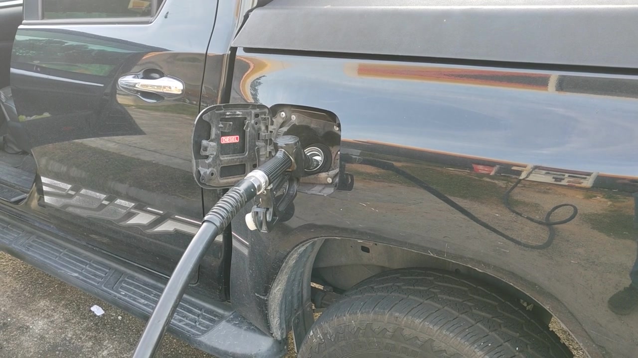 En brændstofdyse indsættes i en bils benzintank for at pumpe benzin. Køretøjet tankes op på en servicestation under en biltur.