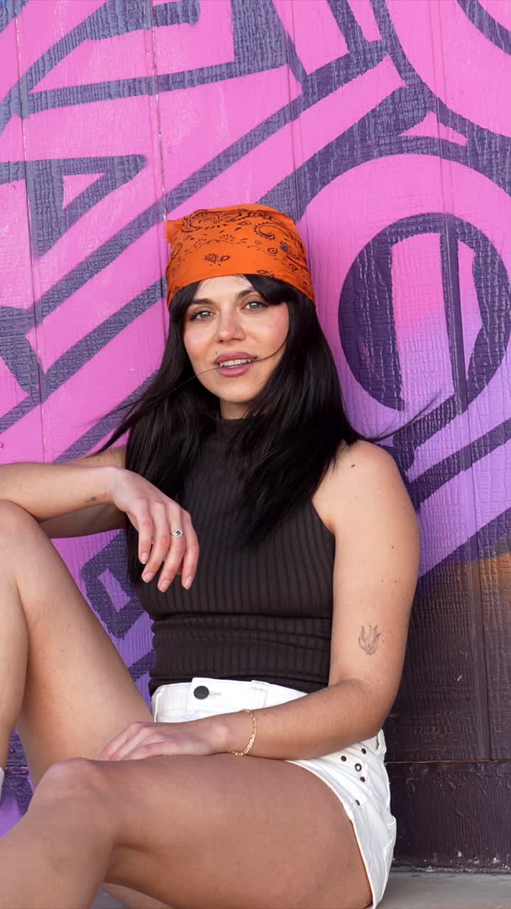 Happy Young Woman Posing Against a Vibrant Graffiti Wall