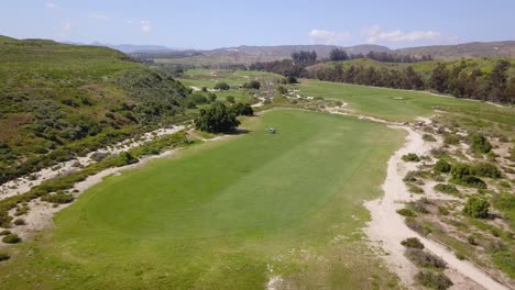 Vista-Aérea-De-Un-Hermoso-Campo-De-Golf-Con-Montañas-Al-Fondo-En-El-Sur-De-California-En-Un-Día-Soleado