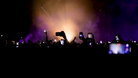 fans dancing and taking pictures with phones in front of live stage