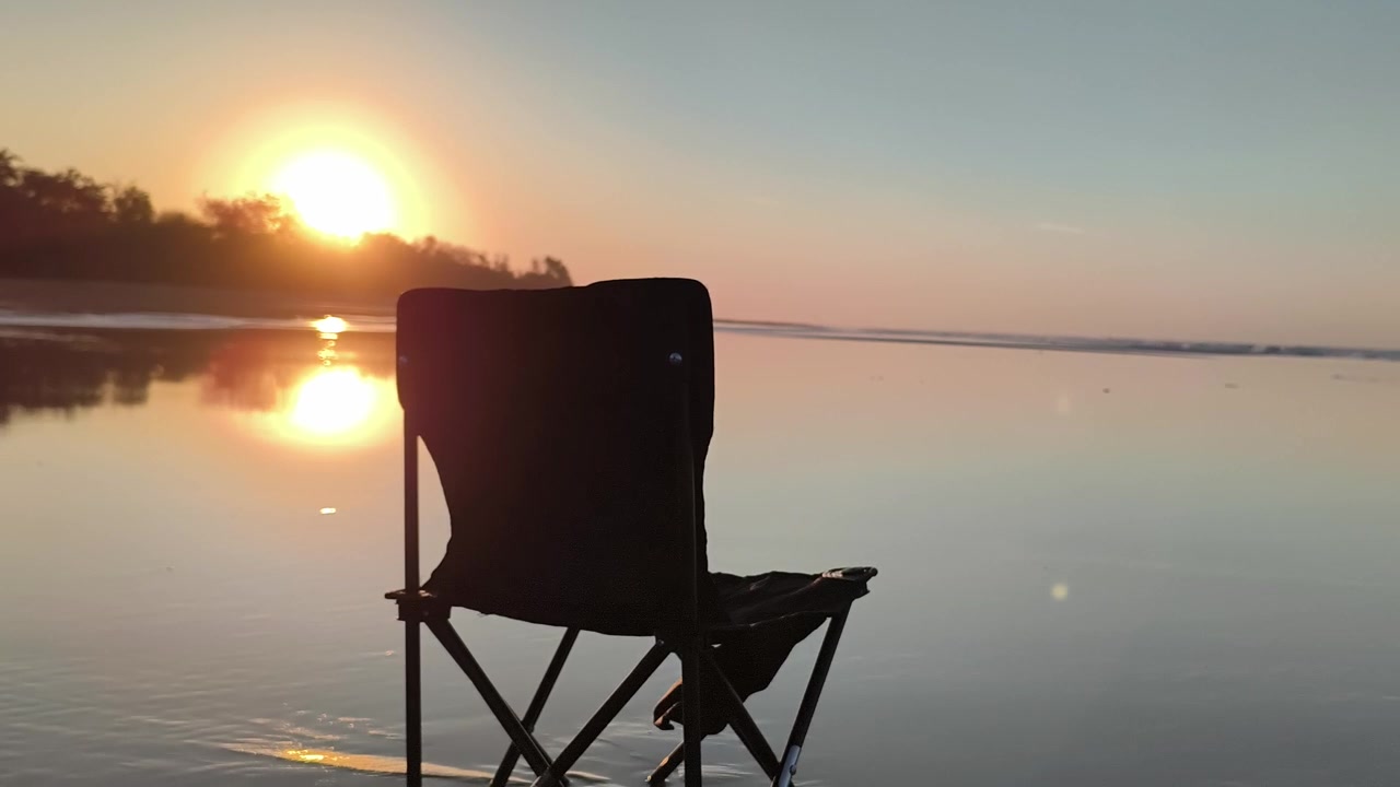 Sedia pieghevole vuota sulla spiaggia al tramonto