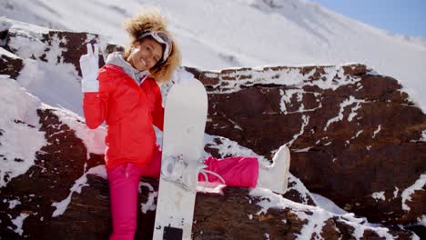 Skier-leaning-on-rocks-with-snowboard