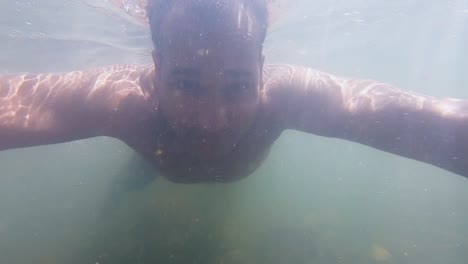 man swimming in dirty water of river underwater view with sunlight beams at morning