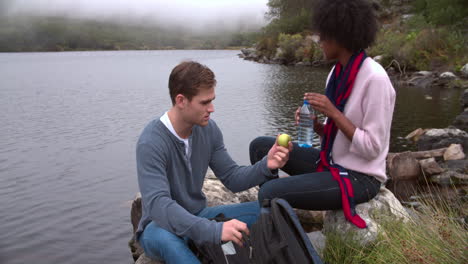 Couple on a walk taking a break by the edge of a lake
