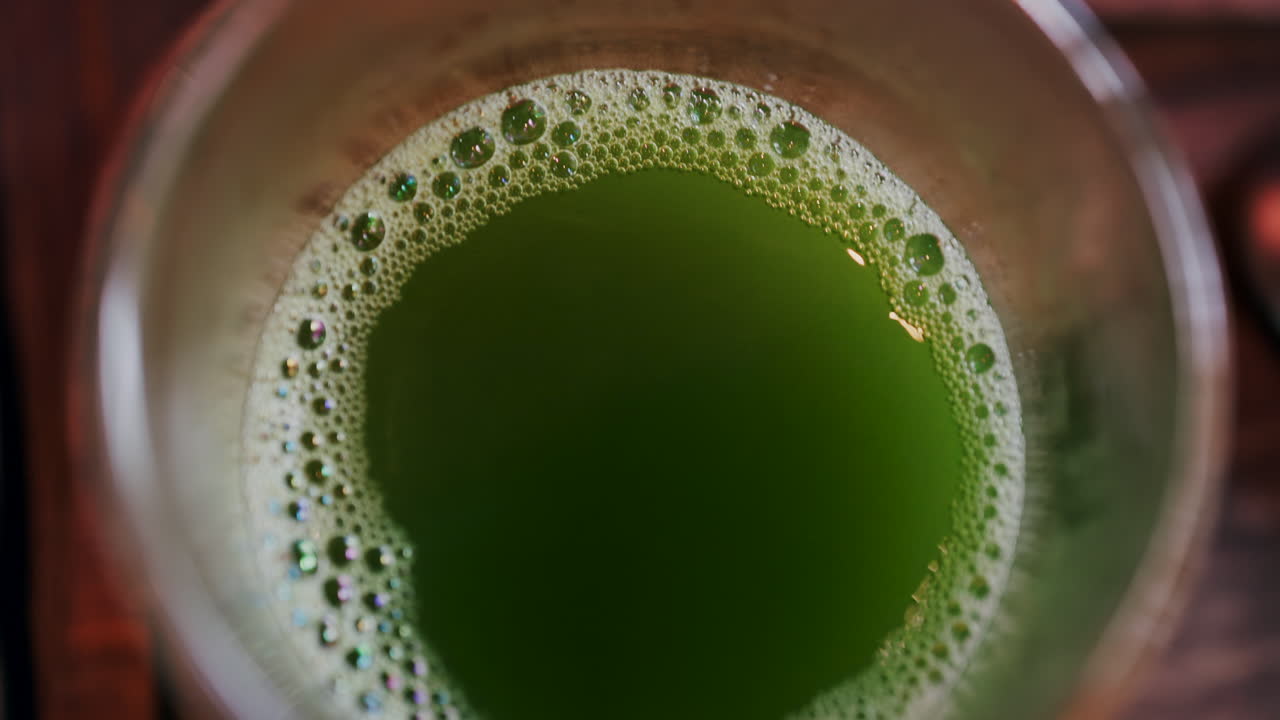Close up of a glass of green tea on a wooden tray on a table