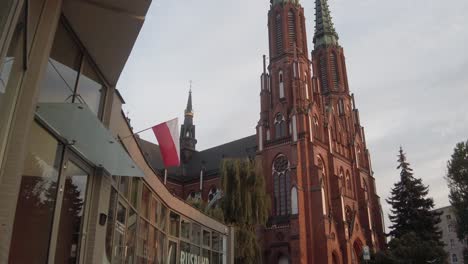 polish flag being waved by the wind in front of a cathedral in warsaw