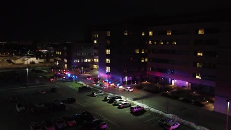 emergency medical service vehicles police and fire trucks outside apartment building at night