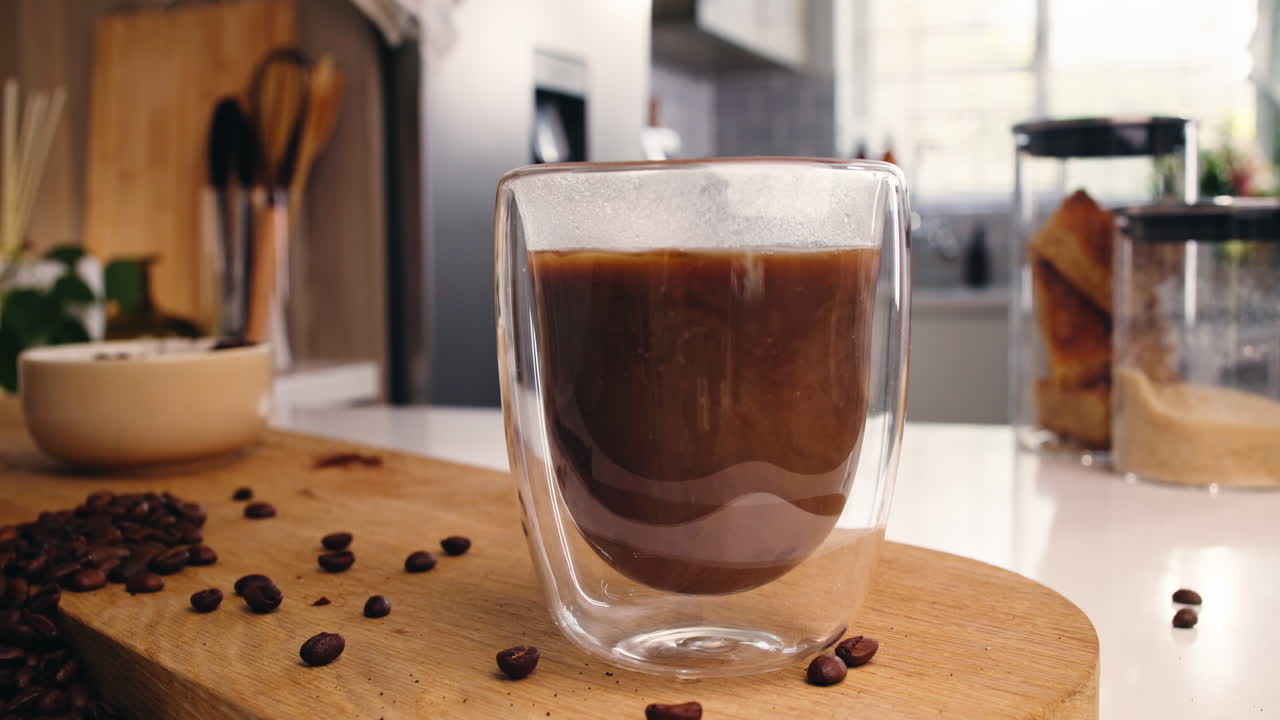 Versare latte in un bicchiere di caffè sul bancone di una cucina